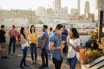 Friends Gathered On Rooftop Terrace For Party With City Skyline In Background
