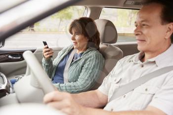 Woman passenger using GPS on smartphone during car journey
