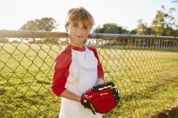 A boy holding baseball mitt and smiling to camera
