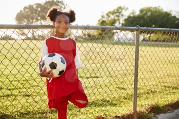 Pre teen black girl holding a soccer ball looking to camera