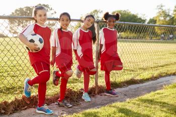 Four pre teen girls in a soccer team looking to camera