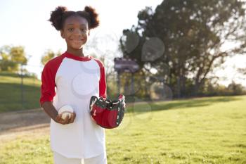 Young Black girl holding baseball and mitt looking to camera