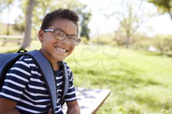 Young mixed race schoolboy in glasses smiling to camera