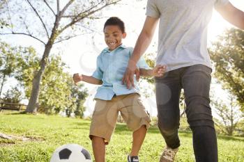 Father And Son Playing Soccer In Park Together