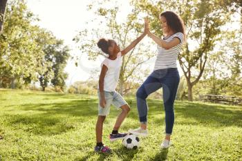 Mother And Daughter Playing Soccer In Park Together