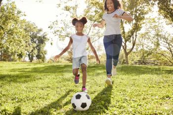 Mother And Daughter Playing Soccer In Park Together