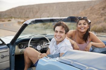 Portrait Of Couple Enjoying Road Trip In Open Top Classic Car