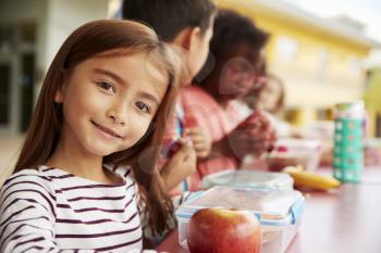 Girl at elementary school lunch table smiling to camera