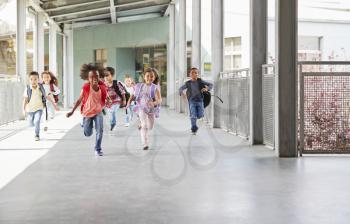 Elementary school kids running to camera in school corridor