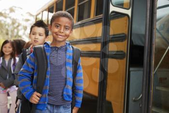 Young black schoolboy and friends wait to get on school bus