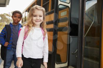 Elementary school girl and boy waiting to board the school bus