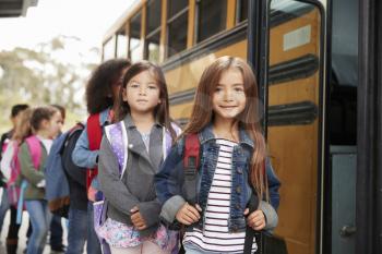 Two girls at the front of the elementary school bus queue