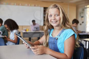 Girl using tablet in school class smiling to camera close up