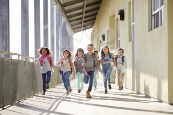 Group of elementary school kids running in a school corridor