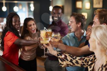 Group Of Friends Standing At Bar And Making A Toast On Night Out