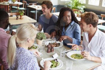 Group Of Friends Sitting At Table In Restaurant Enjoying Meal Together