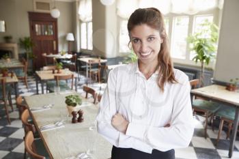 Portrait Of Female Restaurant Manager In Empty Dining Room