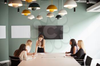 Group Of Businesswomen Sitting Around Boardroom Table And Collaborating On Task At Graduate Recruitment Assessment Day