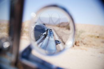 Reflection of desert highway in a car wing mirror