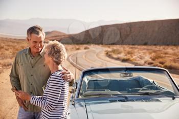 Senior couple checking map on smartphone at desert roadside