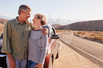 Senior couple stand looking at each other on desert roadside