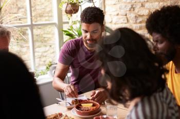 Young mixed race man eating with friends at a dining table
