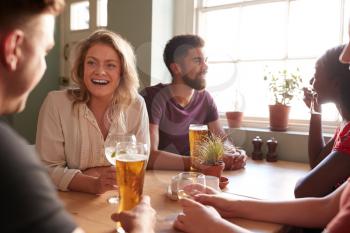 Young adult friends talking at a table in a pub