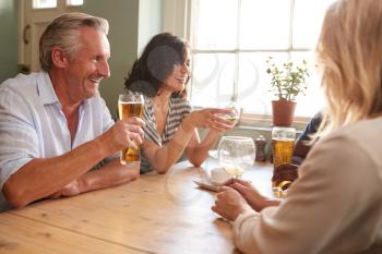 Mature adult friends drinking at a table in a pub