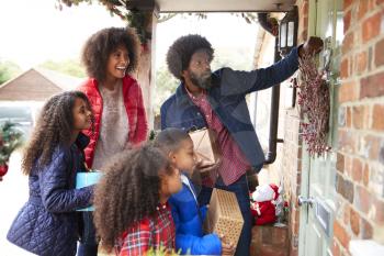 Family Knocking On Front Door As They Arrive For Visit On Christmas Day With Gifts