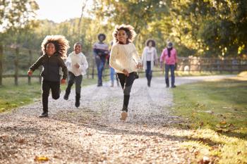 Children Running Ahead As Multi Generation Family Enjoy Autumn Walk In Countryside Together
