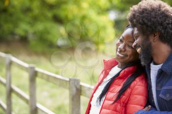 Black adult woman leaning on the shoulder of her boyfriend, standing in the countryside, close up