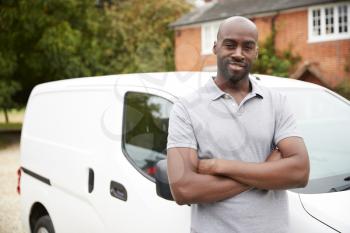Young black adult tradesman standing next to his white van, close up, close up