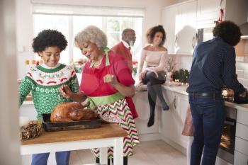 Mixed race, multi generation family talking in the kitchen while they prepare Christmas dinner together