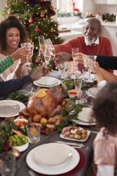Black grandfather making a toast with his family at the Christmas dinner table, elevated view