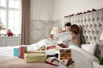 Couple Hugging In Bed At Home As They Exchange Gifts On Christmas Day