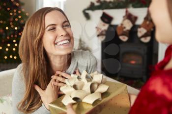 Excited Mother Receiving Christmas Gift From Daughter At Home