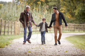 Grandfather With Son And Grandson On Autumn Walk In Countryside Together