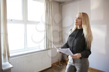 Female Realtor Looking At House Details In Property For Renovation