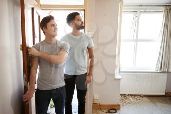 Excited Male Couple Opening Front Door Of New Home