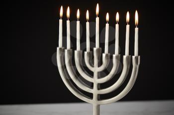 Lit Candles On Metal Hanukkah Menorah On Marble Surface Against Black Studio Background