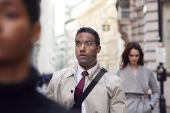 Young black businessman walking in a busy London street looking away, close up