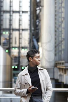 Young black businesswoman standing in the city with smartphone in hand, close up, vertical