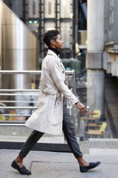 Side view of young black businesswoman walking in the city, London UK, full length