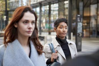 Two young adult businesswomen walking in the city of London, close up, selective focus