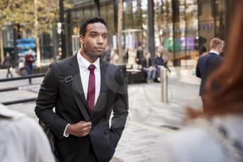 Young black businessman walking in a street in the city, selective focus