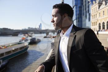 Young back businessman standing at the Thames riverside in the city of London admiring the view, close up