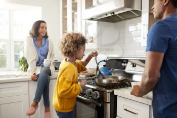 Close up of young family spending time together while preparing food in their kitchen, selective focus