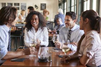Business Colleagues Sitting Around Restaurant Table Drinking Wine