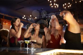 Group Of Female Friends Drinking Shots In Cocktail Bar Together