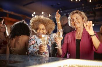 Portrait Of Female Senior Friends Drinking And Dancing In Bar Together